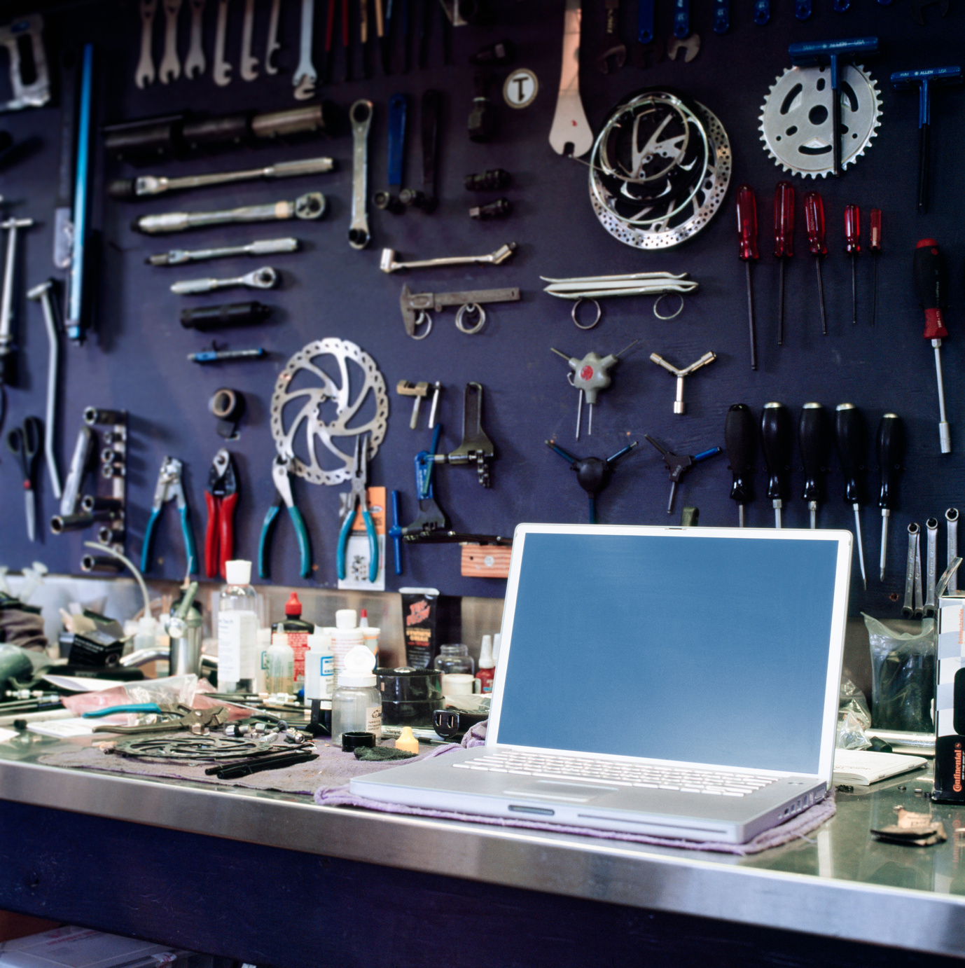 Laptop computer with blank monitor screen on workbench in bike shop. Small businesses staying organized using technology tools.